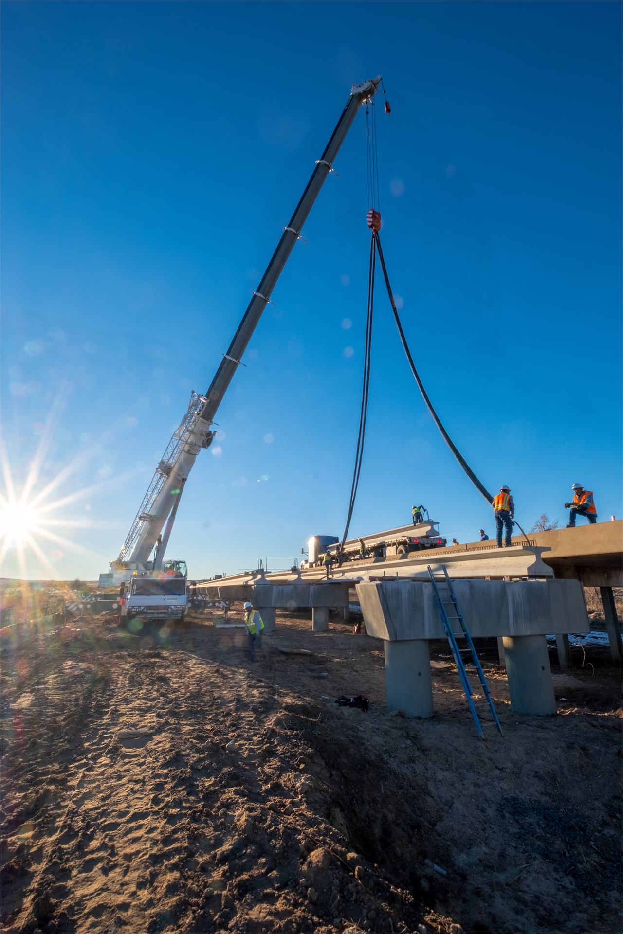 Crane lifting bridge component with sun flare