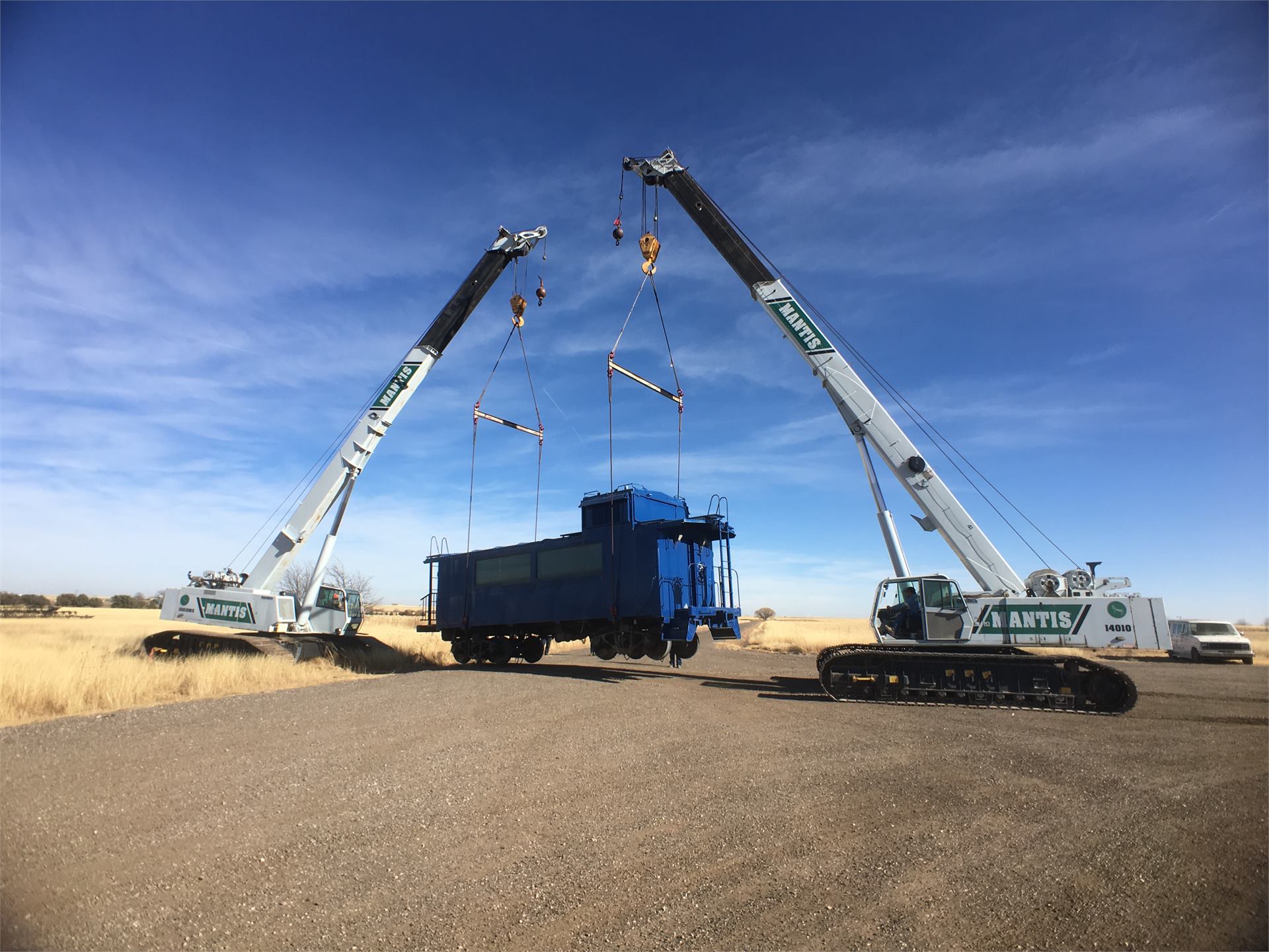 Two Mantis cranes lifting rail car